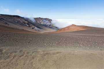 Fototapeta na wymiar Looking down in the Haleakala Crater while clouds are being blown over the mountain ridge