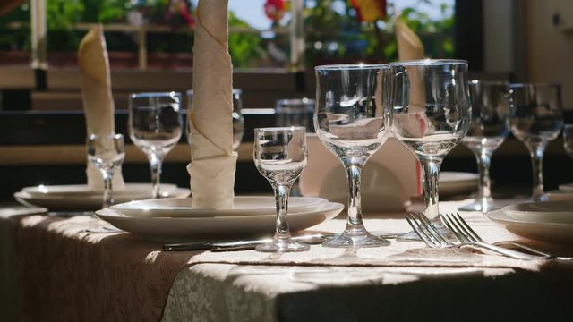 The morning in the restaurant. Through the window the sun is shining on Ruffle glasses and plates.