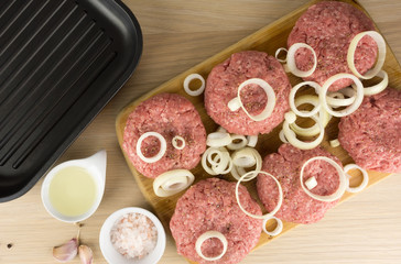 Obraz na płótnie Canvas raw burgers, beef on a cooting board, frying pan on woogen backg