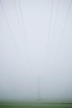 A pylon and cables emerging through fog
