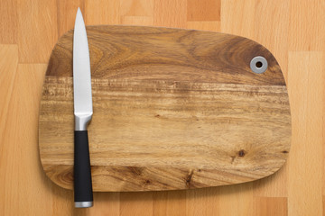 Knife on wooden cutting board on wooden background