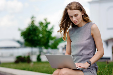 Young woman on the street sitting and working at his laptop