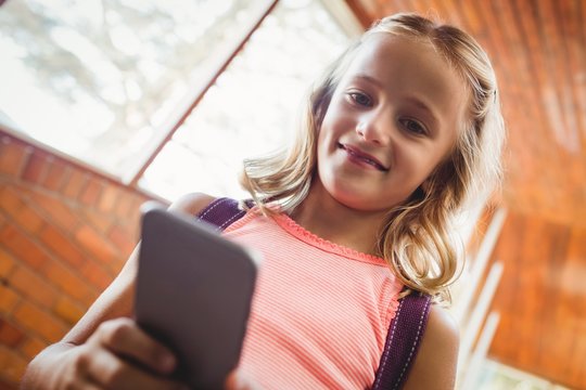 Cute little schoolgirl looking at her smartphone