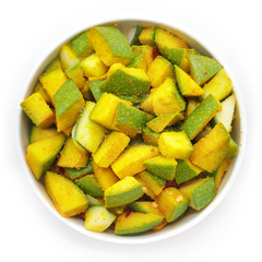 Organic sliced Indian Mango (Mangifera indica), seasoned with turmeric powder and salt in white bowl. Isolated on white background. Top view.