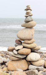 Fototapeta na wymiar Building stone towers on pebble beach on coastline of Lindisfarme island , UK