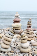 Building towers with  stones on the pebble beach on the Holy Island of Lindisfarne, Northumberland, England, UK, stones and sea 