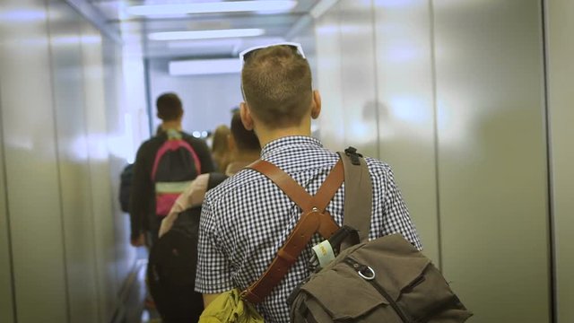 The young man goes down the hall to board the aircraft.
