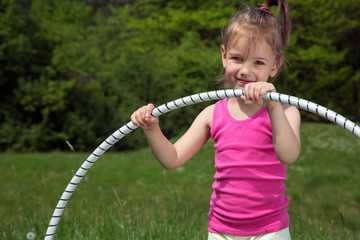Smiling Little Girl With Hula Hoop Enjoying Beautiful Spring Day In The Park
