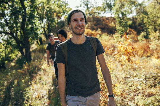 Smiling young man hiking with friends in forest