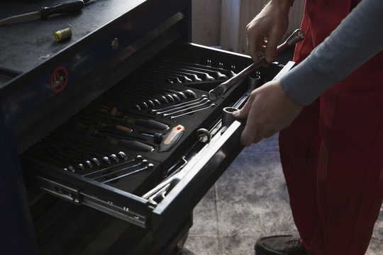 Midsection of mechanic removing tools from drawer at garage