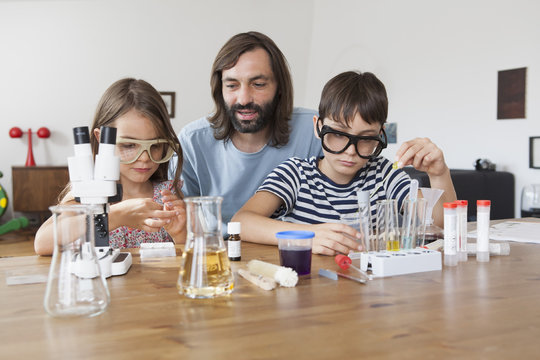 Father assisting children in doing school science project at home