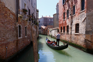 Fototapeta na wymiar Venetian gondolier punting gondola through canal waters of Venic
