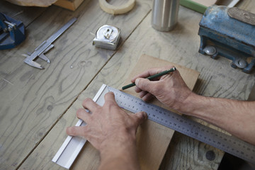 Cropped image of male carpenter marking on plank in workshop