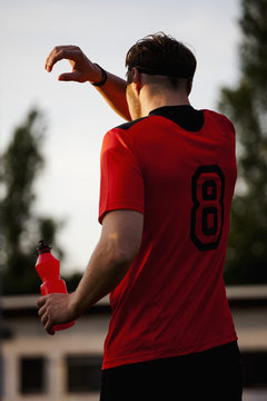 Rear view of tired sportsman cleaning sweat on face