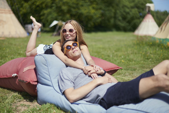 Young couple lying on pillows while glamping, teepee in background