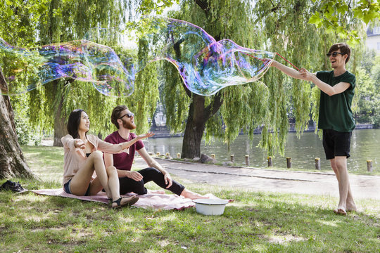 Happy friends enjoying with large bubble at park