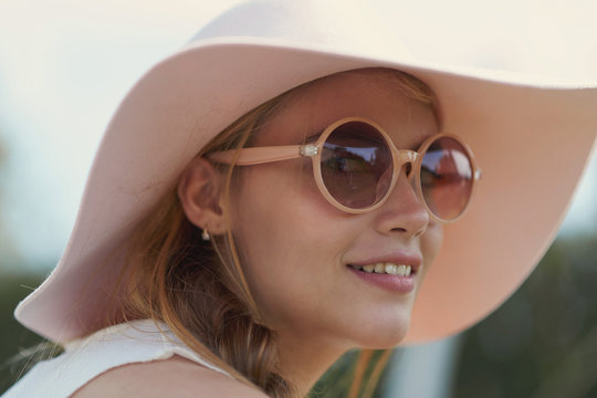 Portrait of young woman wearing sunglasses and hat in park