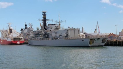 Dolly view of a modern warship in Portsmouth harbour