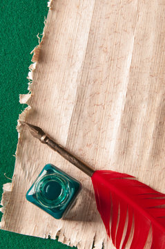 Red quill pen and green inkwell on a papyrus sheet