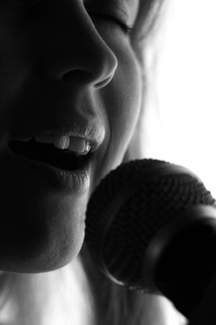 silhouette of a woman singing with a microphone in hands