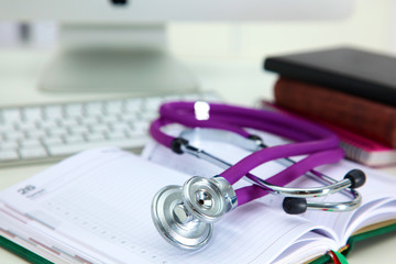 Stethoscope lying on a table on an open book