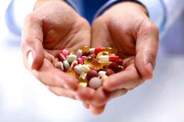 A young doctor holds the patient's hand with pills