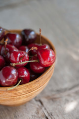 Cherries in a wooden bowl on a wooden table 