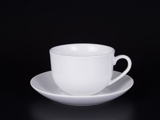 White cup on a saucer isolated on a black background