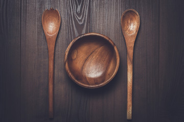 wooden salad bowl and two spoons on the brown table