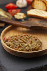 Egplant caviar ( salad ) on a wooden rustic plate over dark table