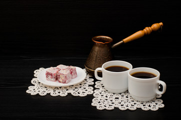 Two mugs of coffee, Turkish delight and cherry pots on a black background