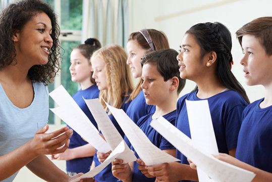 Group Of School Children With Teacher Singing In Choir