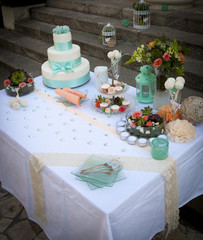 Wedding table arrangement with wedding cake, mini muffins, champagne glasses and other decorations