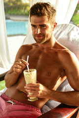 Man Relaxing At Spa, Drinking Cocktail. Beautiful Handsome Healthy Happy Smiling Male With Sexy Body Holding Fresh Detox Milk Drink, Enjoying Summer Vacations In Outdoor Day Spa Salon. Relax, Pleasure