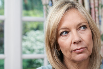 Head And Shoulders Portrait Of Unhappy Mature Woman At Home