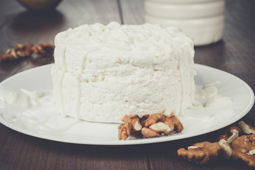 Cottage cheese with Circassian walnut in white plate on wooden table