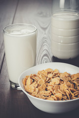 glass of milk and bowl of cornflakes on the table