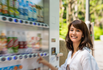 Happy japanese girl choosing soft drink at city dispenser