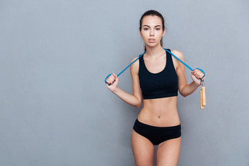 Attractive sport girl holding jumping rope and looking at camera