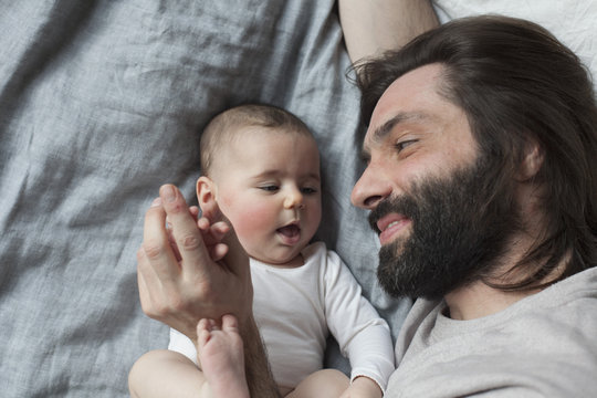 High angle view of affectionate father and baby girl in bed