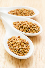 Fenugreek seeds in white spoon.