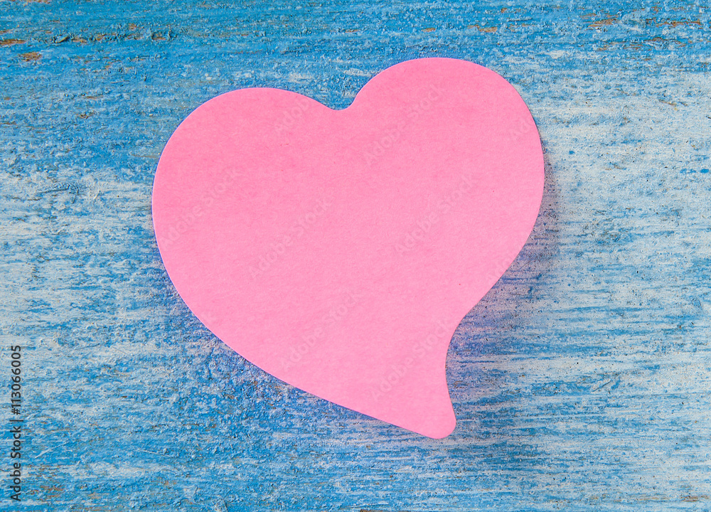 Wall mural Pink label paper heart on blue wooden floor.