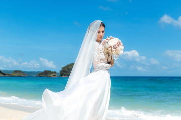 Fototapeta na wymiar Beautiful brunette fiancee in white wedding dress with big long