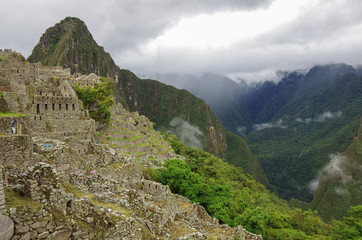 Fototapeta na wymiar View of temple ruins and terrace in Lost Inca City of Machu Picchu. Low clouds and mountains at background. Cusco Region,Sacred Valley, Peru