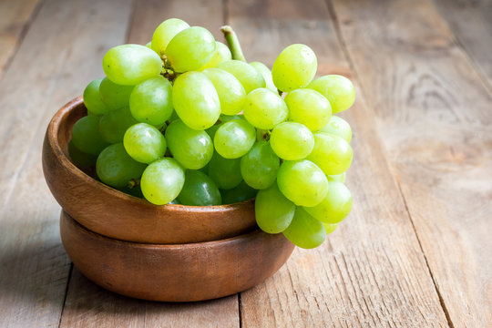 Bunch of green ripe grapes in wooden bowl, copy space