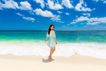 Fototapeta na wymiar Young beautiful Asian girl in blue dress on the beach of a trop