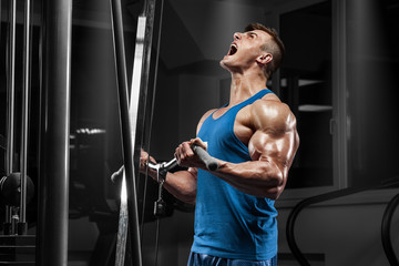 Muscular man working out in gym doing exercises at biceps, strong male