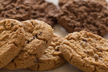Cookies pile with chocolate chip on light textile background. Delicious morning snacks for breakfast, brunch and lunch. Appetizing, healthy, sweet, scrummy, and fast food.