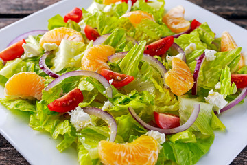 Fresh Mandarin, vegetables salad on wooden table.
