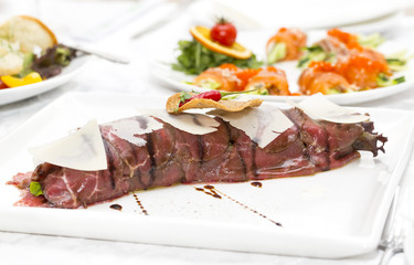 carpaccio with herbs and cheese on white background
